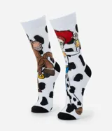 Par de medias de caña larga, blancas con estampado de vaca (manchas negras), con imágenes de los personajes Jessie y Bullseye de Toy Story. Tienen puntera y talón negros.