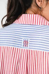 Camisa a rayas rojas y blancas en un lado y azules y blancas en el otro, con corte en A y abertura central con botonadura doble.