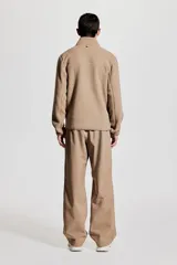 Campera deportiva color beige en tejido sherpa, con cuello alto, cierre frontal, bolsillo superior con cierre, bolsillos laterales con cierre, puños y bajo con elástico fino.