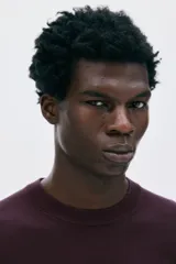 Buzo de punto fino color borgoña, con cuello redondo y corte regular.