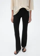 Pantalon de tiro medio con diseño acampanado y entallado, confeccionado en tejido elástico con cintura de goma elástica.