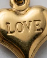 Collar de cadena fina con dije de corazón en relieve grabado con la palabra LOVE, acabado en tono dorado.