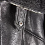 Campera de cuero sintético negro con interior y detalles de corderito sintético en cuello, puños y ruedo. Presenta cierre frontal metálico y bolsillos laterales con cierre.