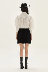 Falda corta de cuero color marrón, con diseño de flecos largos desmontables que cubren toda la prenda. Presenta un estilo western con cierre en la cintura.