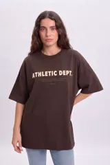 Remera oversize marrón con estampa frontal en color beige que dice "ATHLETIC DEPT.".