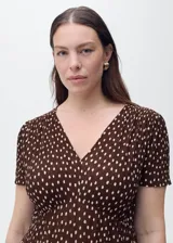 Vestido midi de corte recto con estampado de lunares, cuello en pico y mangas cortas. Presenta cierre de cremallera lateral y abertura en el bajo.