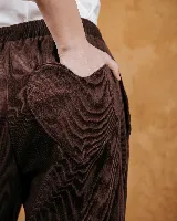 Pantalón de pana color marrón, de corte holgado y largo al tobillo. Presenta cintura elástica, bolsillos delanteros y detalle constructivo en forma de corazón en el bolsillo trasero.