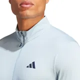 Remera de entrenamiento Adidas color celeste con cierre parcial y logo en el pecho.