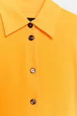 Camisa de viscosa color naranja de la colección ZW Collection de Zara, con cuello solapa, manga larga con puño, bajo asimétrico y cierre frontal con botones a contraste.