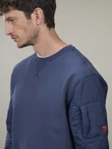 Sweater verde militar de cuello redondo y manga larga con detalle de bolsillo con solapa en la manga izquierda.