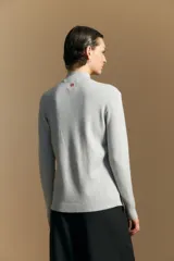 Polera de cuello alto en color blanco, confeccionada en tejido acanalado con un diseño geométrico de relieve que crea un efecto visual estilizado. Presenta un corte al cuerpo y mangas largas, ideal para usar como prenda base o principal.