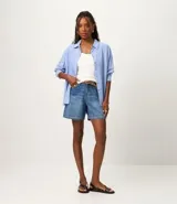 Bermuda de jeans azul claro, con trabillas en la cintura, bolsillos laterales y traseros, y cierre tradicional.