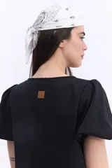 Vestido corto negro con escote en V, mangas cortas abullonadas, silueta suelta y costuras visibles en el frente y la espalda.