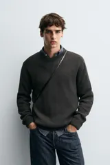 Sweater de punto en canalé color negro, de corte regular fit, cuello redondo y manga larga con terminaciones en rib.