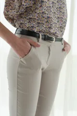 Pantalón chino color beige de corte cigarette, con bolsillos laterales y traseros. Se ajusta a la cintura con cinturón de cuero negro.