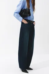 Jean de denim azul oscuro con diseño de piernas curvas y corte holgado de tiro medio.