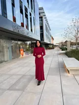 Vestido largo color borgoña, de corte ajustado, con cuello alto y mangas largas.