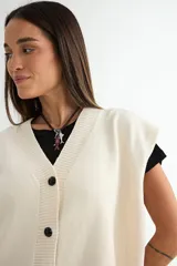 Chaleco de punto color verde, con escote en V y cierre frontal de botones negros. Presenta un diseño holgado con terminaciones acanaladas en el cuello, sisas y ruedo.