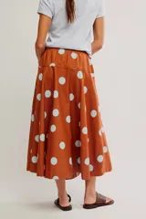 Falda midi de corte A y cintura baja, confeccionada en popelina de algodón color marrón terracota con estampado de lunares celestes.