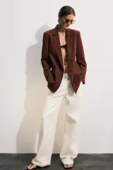 Blazer marrón de cuello solapa con muescas, manga larga y bolsillos de vivo con solapa. Cierre frontal con un botón.