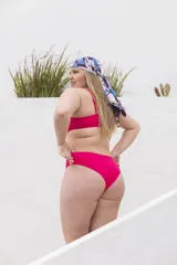 Conjunto de bikini rosado con corpiño triangular con lazo en el centro y bombacha clásica con corte en V.