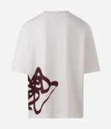 Remera oversized de algodón color blanco, de corte amplio y descontracturado, con cuello redondo, mangas cortas y gran estampa frontal localizada de inspiración urbana en tono bordó.