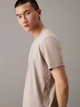 Remera de punto de algodón en color beige claro, con cuello redondo y corte regular. Presenta una cinta con logo en espiguilla de Calvin Klein en los laterales.