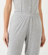 Pijama de dos piezas color gris con lunares blancos. La remera es de manga corta, cuello redondo, con botones frontales y detalle en los hombros. El pantalón es largo con cintura elástica.