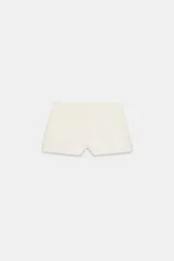 Bermudas de tiro medio y color beige, con cintura ancha, bolsillos delanteros y falsos bolsillos con solapa en la espalda. Presenta cierre frontal con cremallera y ganchos metálicos.