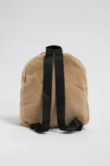Mochila de textura suave tipo sherpa en color beige, con compartimento principal y bolsillo frontal con cierre. Incluye correas negras ajustables.