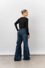 Jean de tiro alto con corte wide leg y pierna amplia. Confeccionado en denim rígido de lavado azul clásico, cuenta con bolsillos funcionales y cierre frontal.
