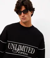 Buzo negro de cuello redondo, manga larga y calce boxy, confeccionado en mezcla de algodón y poliéster. Presenta recortes horizontales con vivos blancos en el pecho y las mangas, además de un diseño bordado con la inscripción "Unlimited Series".