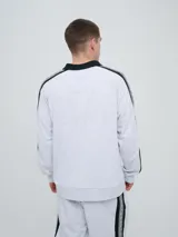 Buzo deportivo Umbro modelo Mixtape, color negro con cuello polo blanco y franjas blancas en las mangas con logo de la marca. Cuenta con puños y cintura elastizados.