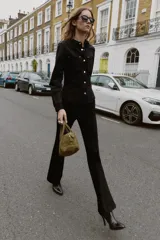 Camisa entallada color marrón oscuro, con cuello camisero y manga larga. Presenta dos bolsillos de plastrón en el delantero y cierre frontal con botones a presión dorados.