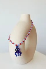 Collar corto con cuentas de plástico amarillas y verdes, y dije de vidrio con forma de pulpo negro.