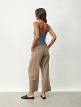 Pantalón de vestir color tostado de corte ancho y relajado, tiro alto con trabillas para cinturón, pinzas frontales y bolsillos laterales.