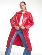 Chaqueta larga de charol color rojo, con cuello solapa y cierre frontal mediante botones metálicos plateados. Presenta un diseño de silueta recta, mangas largas y bolsillos verticales, con un acabado brillante e impermeable.