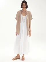 Vestido largo blanco de breteles finos, corte holgado y escote redondo. Incluye dos collares de cuentas y sandalias bajas con tiras.