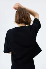 Remera de corte boxy en punto suave de algodón, con cuello redondo, hombros caídos y mangas cortas al codo.