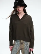 Sweater de punto color verde oliva, con cuello polo abierto en V, manga larga con hombros caídos y terminaciones acanaladas en puños y ruedo.