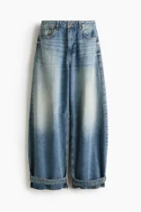 Jean de cinco bolsillos en denim de algodón rígido, con piernas maxivolumen de diseño curvo y corte estándar de cadera a muslo, ligeramente ceñidas en el bajo mediante trabilla. Cuenta con cintura de tiro alto, cierre y botón.