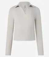 Blusa de manga larga confeccionada en tejido rib de algodón con elastano. Presenta un diseño ajustado al cuerpo con cuello polo y escote en V.