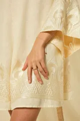 Minivestido blanco de lino con escote en V, mangas anchas acampanadas y bordados dorados en los puños, el dobladillo y el cinturón ajustable.