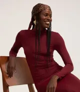 Vestido midi color bordó, de microfibra ligera, con cuello alto fruncido, manga larga, hombreras y detalle fruncido lateral.