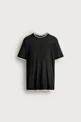 Remera relaxed fit confeccionada en tejido ligero de lyocell, de color negro con cuello redondo, manga corta y acabados en efecto doble combinado a contraste en color blanco.