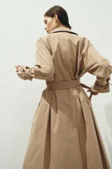 Gabardina midi de doble botonadura con diseño oversized, solapas de muesca, cierre frontal con botones y cinturón extraíble para atar en la cintura. Presenta mangas raglán con trabillas ajustables en los puños, bolsillos laterales y abertura posterior.