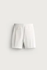 Bermuda regular fit de tejido elástico color blanco, con cintura elástica ajustable mediante cordón, bolsillos delanteros y bolsillos traseros de vivo.