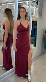 Vestido largo bordó con brillo, de corte sirena, escote en V y tirantes finos cruzados en la espalda. Cuenta con un tajo lateral profundo en la pierna.