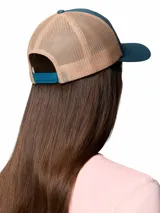 Gorro trucker Columbia de color verde azulado y beige, con paneles de malla trasera y un parche frontal estampado con un oso y la marca.
