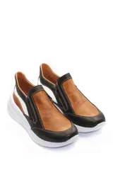 Zapatilla deportiva marrón de cuero liso con detalles en beige y plateado. Presenta cierre lateral y suela gruesa blanca.
